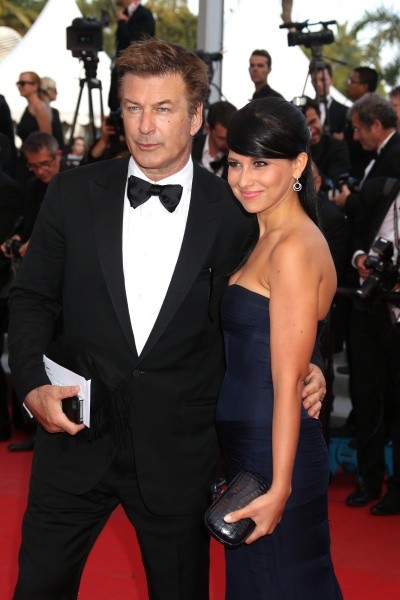 Photo of Alec Baldwin holding the hand of Hilaria Thomas, as they both stand on a red carpet in formal clothes