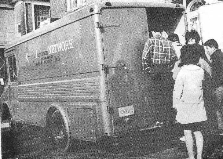 A photo of an old van with students lined up at the back and the words 'Computer Instruction Network' on the side