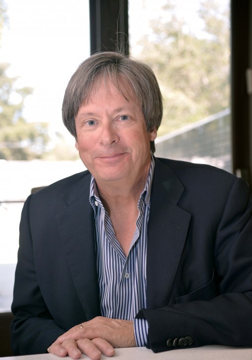 Dave Barry photo, with Dave Barry in a blue suit, sitting at a table, smiling politely