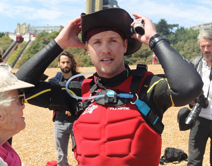 Photo of Sam Branson in kite-surfing gear, smiling, in a weird Colonial-style (or Aussie-style?) hat