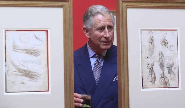 Photo of Prince Charles, peering between two framed hanging sketches
