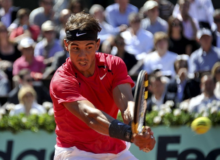 Photo of Rafael Nadal blasting a backhand at the French Open, in a red shirt and black headband