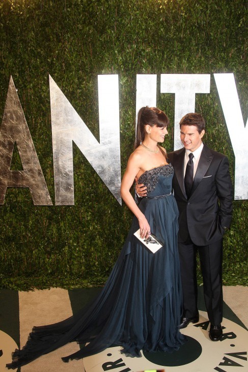 Photo of Katie Holmes and Tom Cruise in formal clothes in front of a VANITY FAIR sign