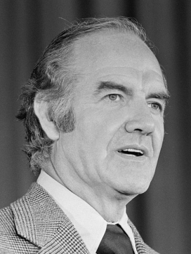 A photo of George McGovern with wavy hair and sideburns in a checked suit