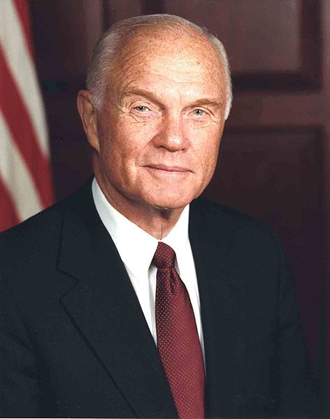 John Glenn in a blue suit and red tie in an official photo, now balding