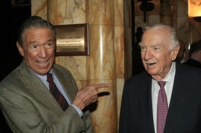 Photo of Mike Wallace pointing a finger in a jovial way at Walter Cronkite, both grinning