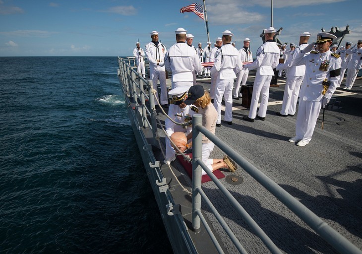 Photo of Neil Armstrong's wife Carol kneeling with his urn beside the ship's railing