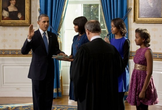 Photo of Barack Obama swear-in, with him standing amid family with his hand on a Bible