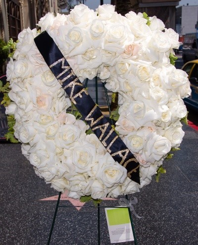 Photo of a wreath of white roses with a banner reading 'Mike Wallace,' over the Mike Wallace walk of fame star