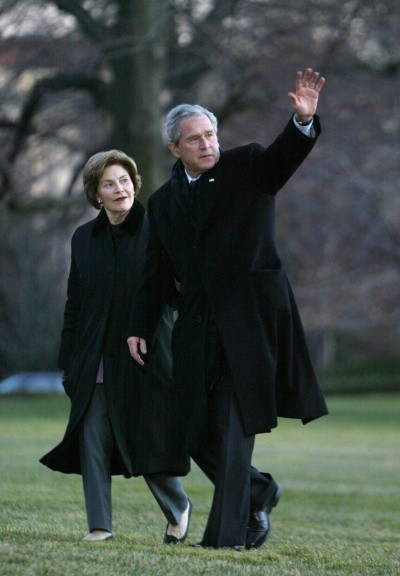 Photo of George W. Bush waving as he and Laura Bush walk across the White House lawn
