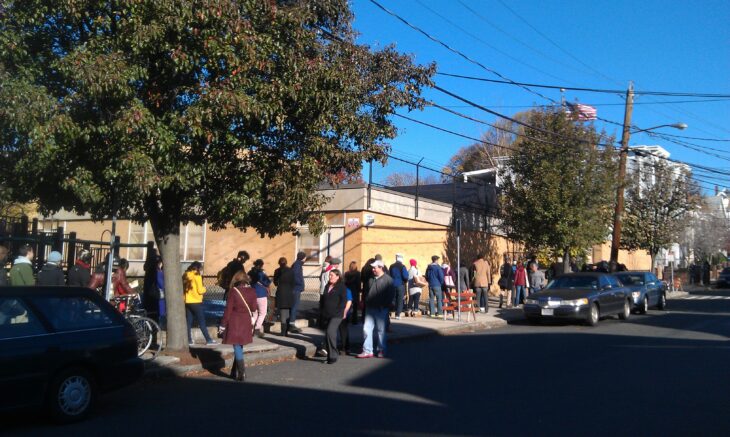 A photo of a street in front of an elementary school with voters in line down the block