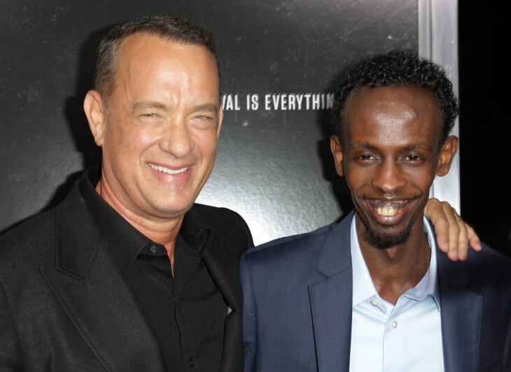 A photo of Barkhad Abdi smiling, arm in arm with Tom Hanks