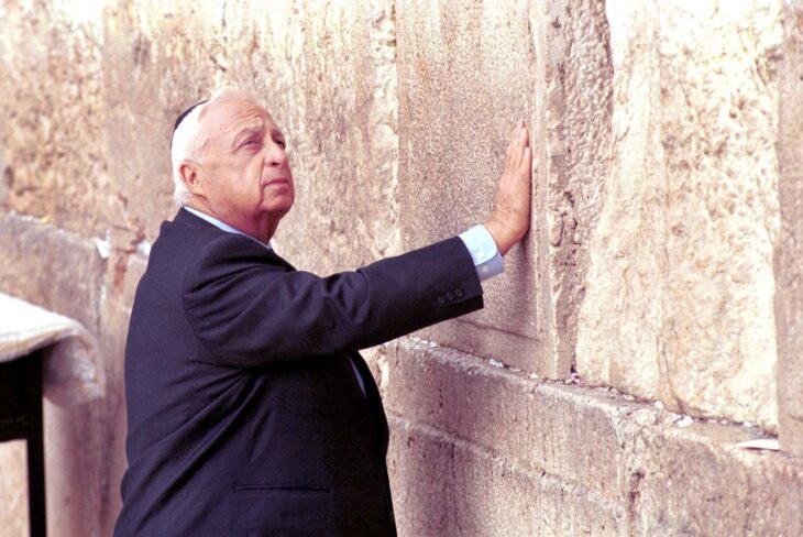 Photo of Ariel Sharon in a yarmulke, with his hand on the Western Wall, looking somber