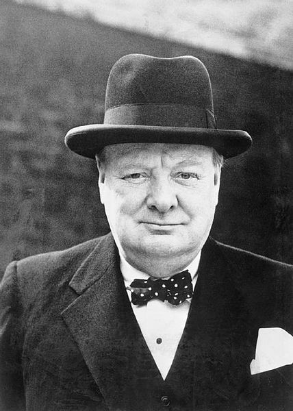 A photo of Winston Churchill in a bow tie and homburg hat, smiling slightly