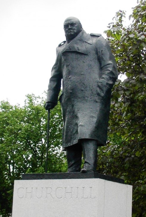 Statue of Winston Churchill standing defiantly in a raincoat and cane
