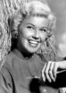 Doris Day leans against a tree trunk (real or fake) and smiles broadly for the camera