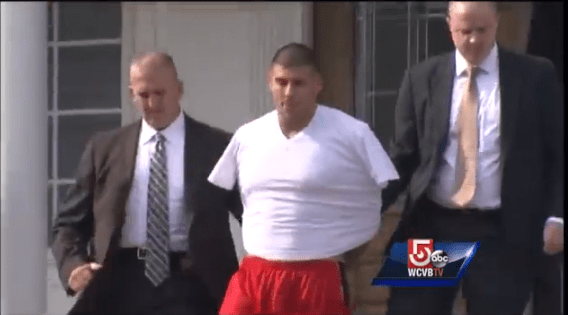Photo of Aaron Hernandez being led from his home in handcuffs