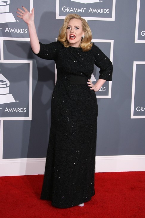 Photo of Adele in a long black gown, giving a jaunty wave on the Grammy red carpet