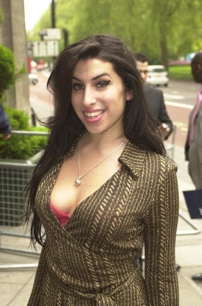 Photo of Amy Winehouse smiling vibrantly on the street, with dark hair