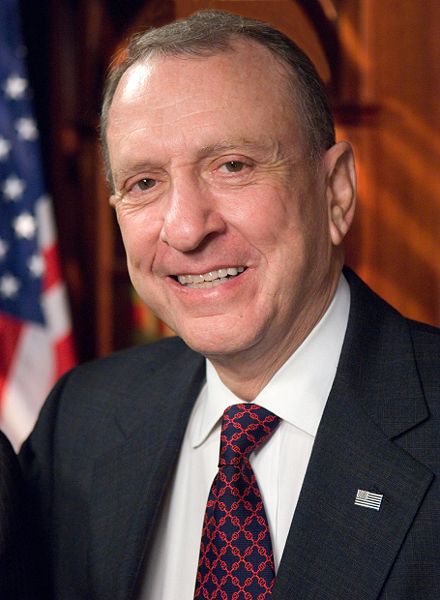 Photo of Arlen Specter in a blue suit and red tie, in an official Senate portrait