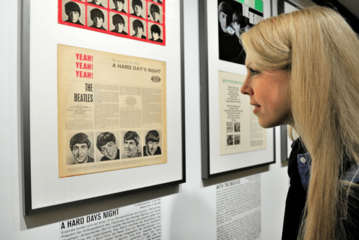 An attractive blonde patron peers at a Beatles album cover on the wall of the Beatlemania museum