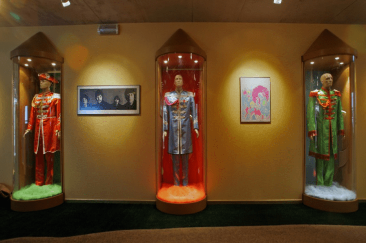 Sgt. Pepper costumes under glass domes draped on odd blank-faced manequins
