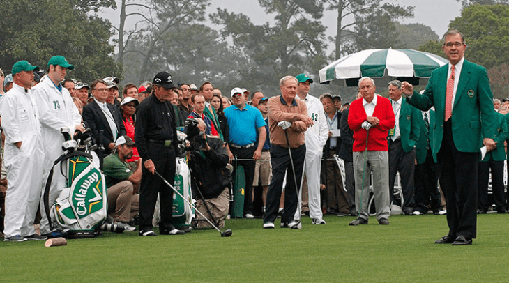 Photo of three old golfers listening as a guy in a green jacket talks