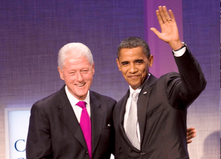 Photo of Bill Clinton on stage with Barack Obama, both men smiling and waving to fans