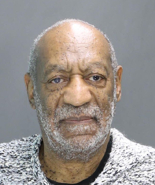 Mug shot of Bill Cosby, in a grizzled gay beard and salt-and-pepper sweater, looking grim