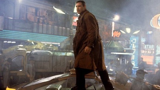 A photo of Harrison Ford as Deckard, standing atop a car while hunting a suspect in Blade Runner