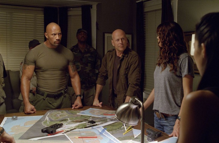A photo of super-muscular Dwayne Johnson standing at a war room table next to confident-looking Bruce Willis