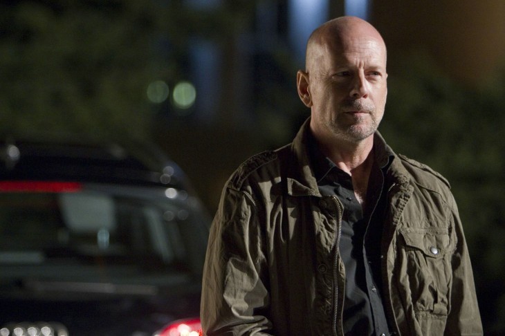 Photo of Bruce Willis in a khaki-style jacket, smiling slightly in the night