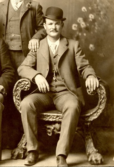 A photo of Butch Cassidy in a suit, sitting for a formal old-time portrait in a bowler hat