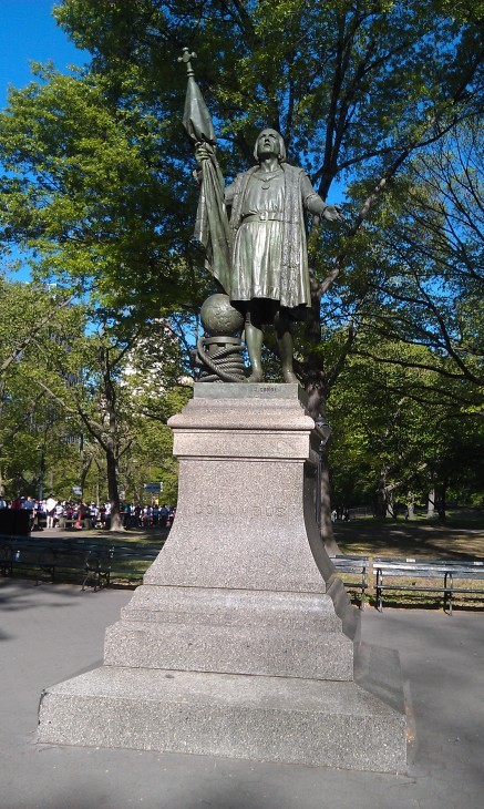 A statue of Columbus in Central Park, raising his hands with a globe and rope at his feet