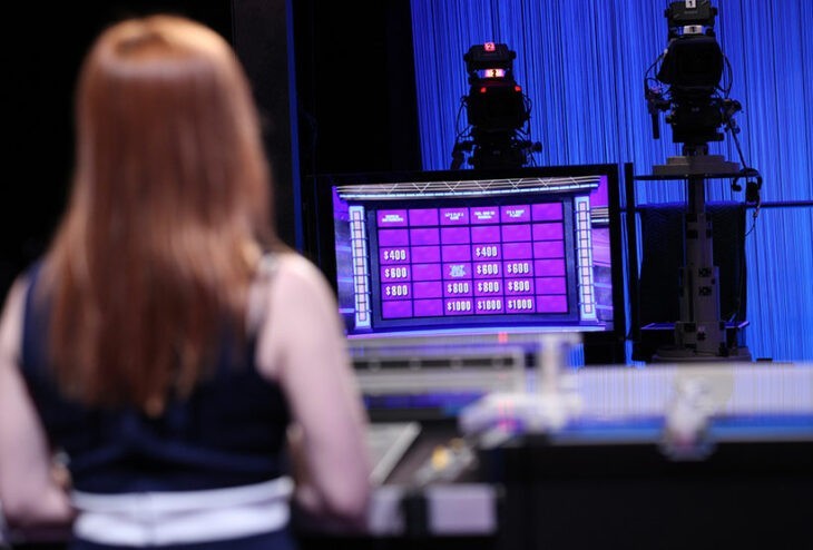 Photo of Pam Mueller looking at a monitor of the Jeopardy game board