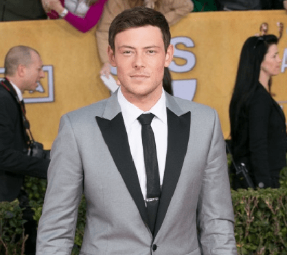 Photo of Cory Monteith in a tuxedo, standing on a red carpet, a few months before his death