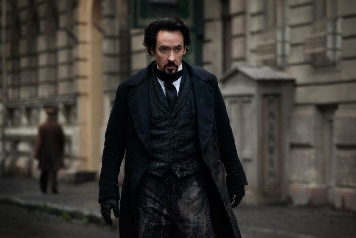 A photo of John Cusack as Edgar Allan Poe, dressed in black, walking down a muddy street like a gunslinger (with no guy)