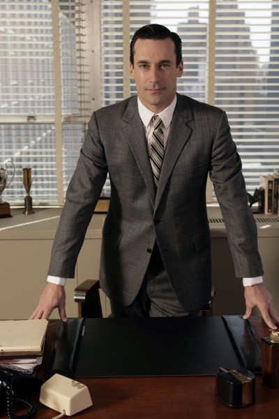 A photo of Don Draper in his office, hands on desk, half-smiling at the camera