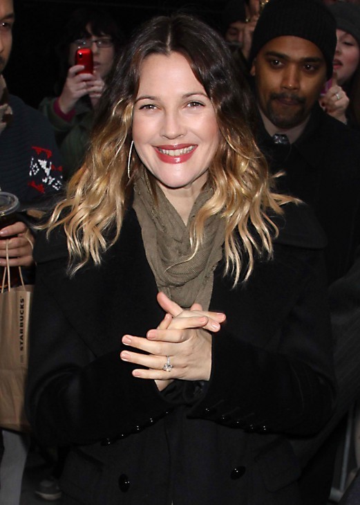 Photo of Drew Barrymore smiling for cameras in front of fans and photographers