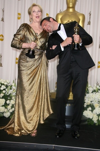 Jean Dujardin, in tux, smiles as he lays his head on Meryl Streep's shoulder