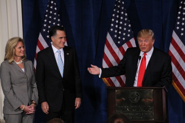 Donald Trump gestures at Mitt Romney and wife, all smiling