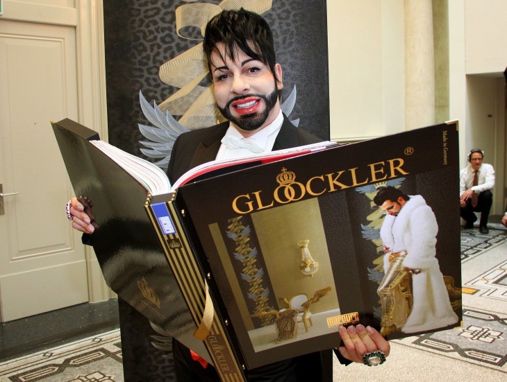 Photo of Harald Gloeoeckler, holding up a huge coffee-table book of his interior designs