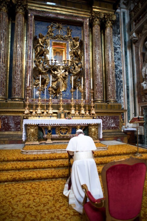 Photo of Pope Francis I, in white robes, kneeling at a fancy altar