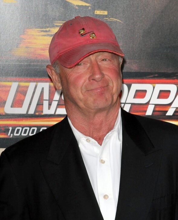 Photo of Tony Scott in his red baseball cap and a black suit, smiling