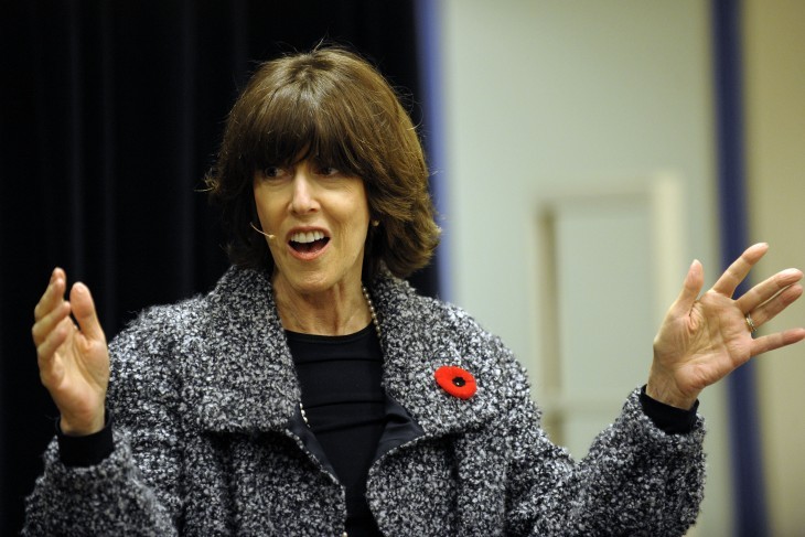 Photo of Nora Ephron with a small microphone on, talking to a crowd while waving her arms