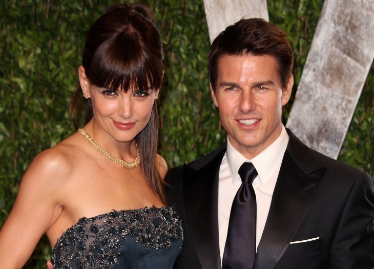 Photo of Katie Holmes in a blue gown, smiling next to Tom Cruise in black suit, on a red carpet