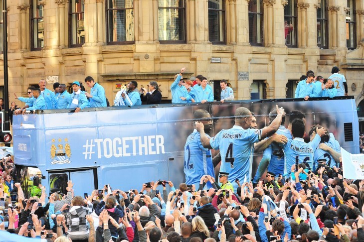 A closer shot of the bus loaded with Manchester City football players as they wave to huge crowds