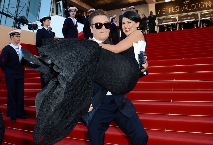 Photo of Alec Baldwin carrying Hilaria Thomas up a red-carpeted stair at Cannes