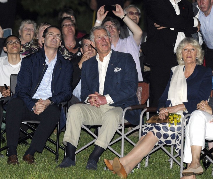 Photo of Prince Charles in casual clothes (casual for him, that is -- blue sportcoat) in a folding chair, watching fireworks