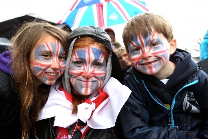 A family with faces painted in the Union Jack smile for the camera